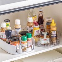 TextPlastic 360 degree rotation storage tray for refrigerator shelf holding seasoning bottles with raised edges and handles.